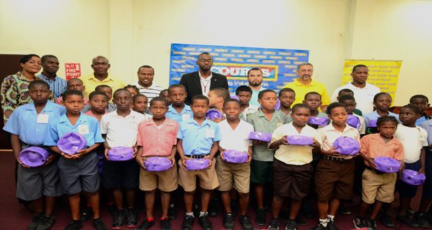Director of Sport Christopher Jones takes a photo opportunity with sponsor and Pee Wee footballers from various schools as they display their gifts at the COURTS Pee Wee U-11 Schools Football launch. (Adrian Narine photo)