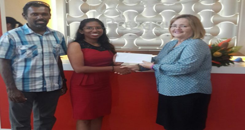 Pegasus’ Susan Isaacs (R) hands over the sponsorship cheque to Vidushi Persaud in the presence of Ryan McKinnon.