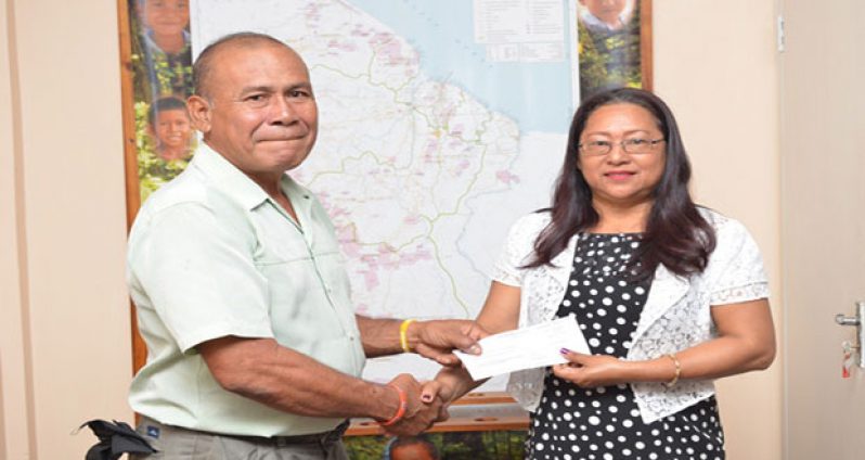 Minister of Amerindian Affairs Pauline Sukhai  handing over a cheque to Manoel “King Perai” Ferreira at the Ministry of Amerindian Affairs, Thomas and  Quamina Streets