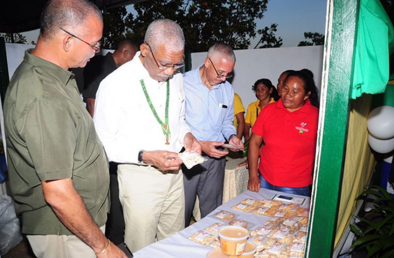 President David Granger examines the packaging and labels of a product on sale at the RACE on Friday in Lethem, Region Nine (Delano Williams)