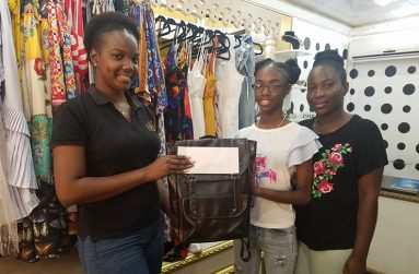 Pieces and Things representative Zari Dyer (left) presents the cheque and backpack to Kijana James (centre) and her mother Karlene Barrow at the Pieces and Things location on North Road.