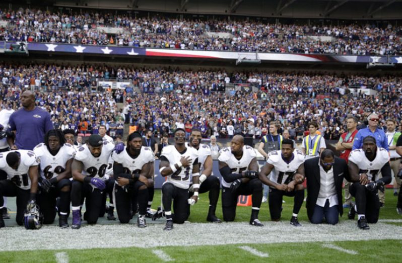 Baltimore Ravens players, including former player Ray Lewis, second from right, kneel down during the U.S. national anthem before an NFL football game.