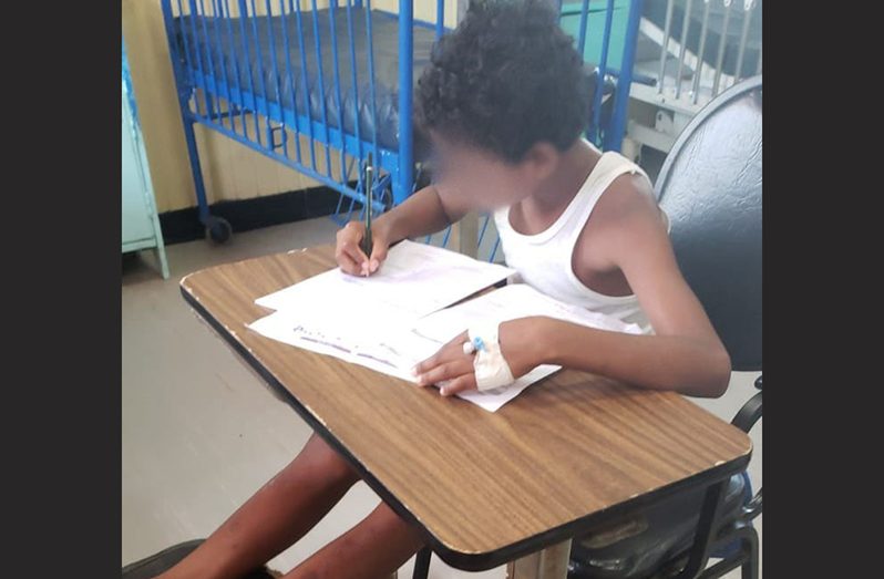 Eleven-year-old Reyon Hersham writing his ‘exam’ while in hospital