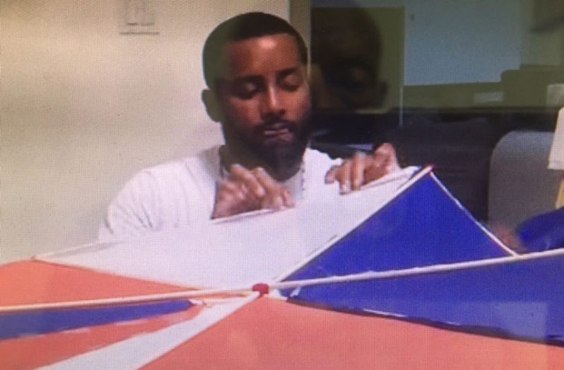 Haitian master kite maker at work on a large kite with the Haitian colours
