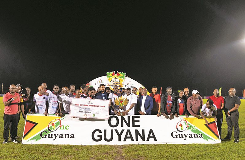 Region Four skipper, Daniel Wilson (left) grips the One Guyana Cup trophy along with Prime Minister (Brig. Rtd.) Mark Phillips following his side's 2-1 win over Region Three.