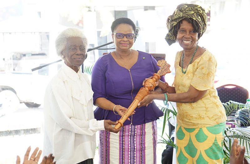 Penda Guyan presenting the baton to Minister of Public Health, Hon. Volda Lawrence, along with Dr. Joycelynne Loncke.