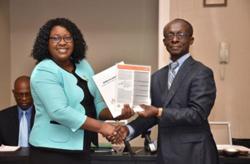 Minister within the Ministry of Public Health, Dr. Karen Cummings, receives a copy of the report from Pan American Health Organization/ World Health Organisation (PAHO/WHO) Country Representative, Dr. William Adu-Krow