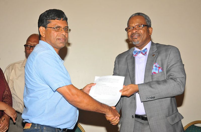 Managing Director of Nand Persaud and Company Limited, Ragindra Persaud and Vice Chancellor of UG, Professor Ivelaw Griffith shake hands as they display the Memorandum of Understanding (MoU) they signed on Thursday
