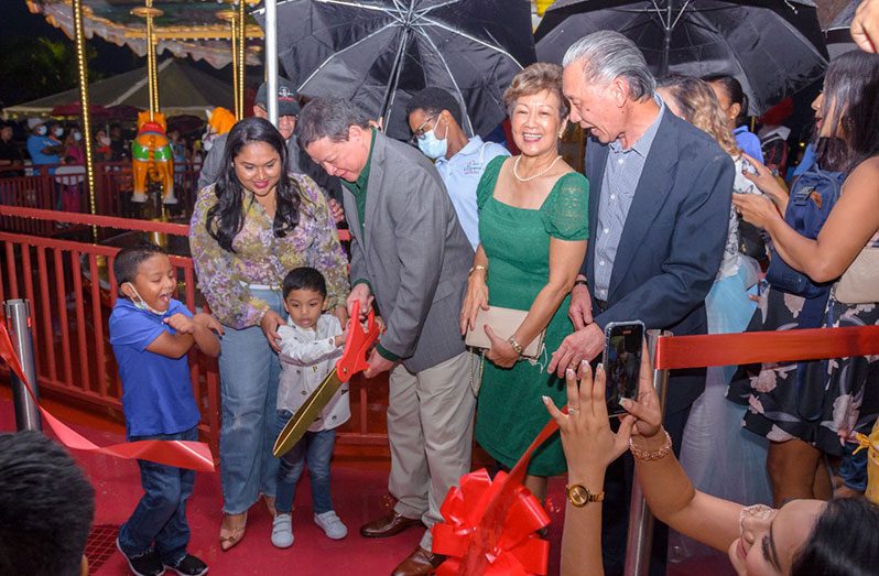 First Lady Arya Ali and her son, Zayd, help MovieTowne’s Chairman, Derek Chin cut the ribbon to officially open the carousel and train rides