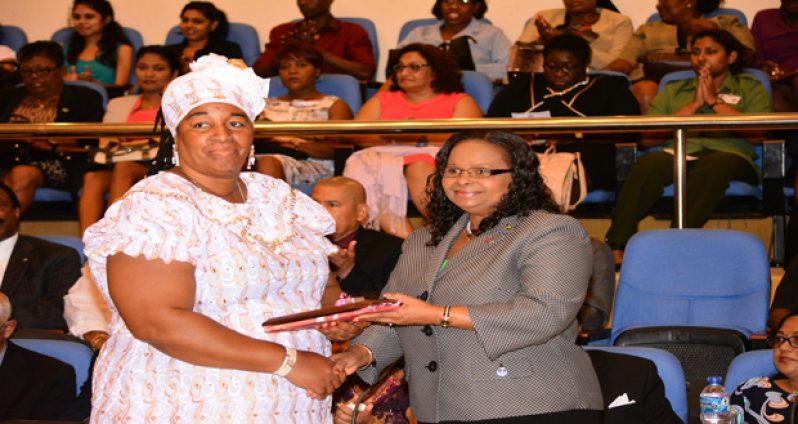 Minister of Social Protection Volda Lawrence presents Ms Ann Baker with her award  on the occasion of International Women’s Day.