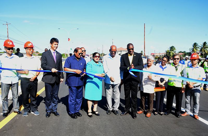 Helping Mrs. Sita Nagamootoo cut the traditional ribbon to officially declare open the enhanced East Coast Public Road are, from left, China’s Ambassador to Guyana, His Excellency Cui Jianchum; her husband,    
Prime Minister Moses Nagamootoo; Minister of Finance Winston Jordan; Minister of Public Infrastructure David Patterson; and  Minister within the Ministry of Public Infrastructure, Jaipaul Sharma