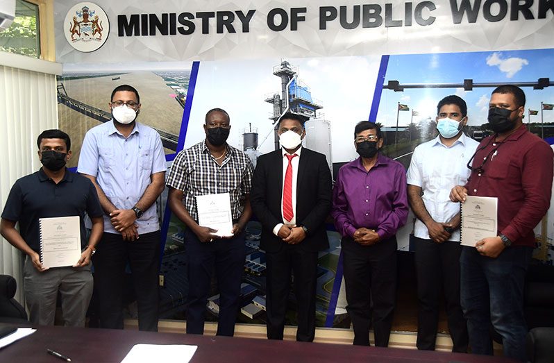 Minister within the Ministry of Public Works, Deodat Indar, centre, and the contractors following the simple signing ceremony at the Ministry of Public Works on Thursday (Adrian Narine photo)