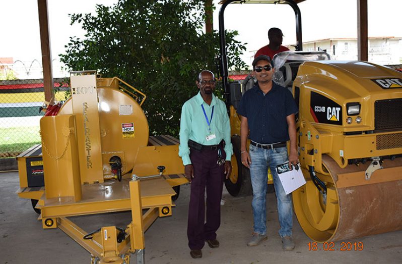 REO Ovid Morrison (left) and Regional Engineer Dhanpaul Sukha pose with the two new pieces of road- repair and maintenance equipment received, for use in Region Five