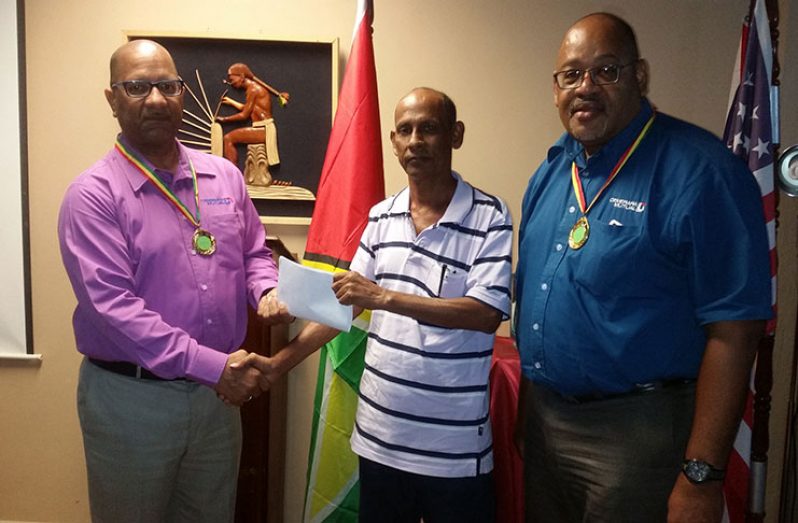 RHTY&SC Asst. organising secretary,Robbie Kissoonlall receives sponsorship from DMLAS Geoffrey Brewster and Clarence Perry.