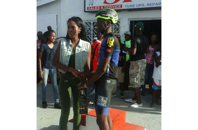Romello Crawford (right) accepts his prize for winning the Benjamin Sports Store 50-mile cycle road race on Monday, from Ashley Benjamin, daughter of Wilbert Benjamin.