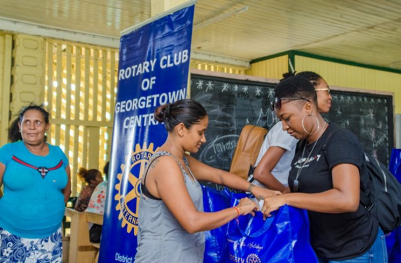 One of the Rotaract members handing over a food hamper to a resident