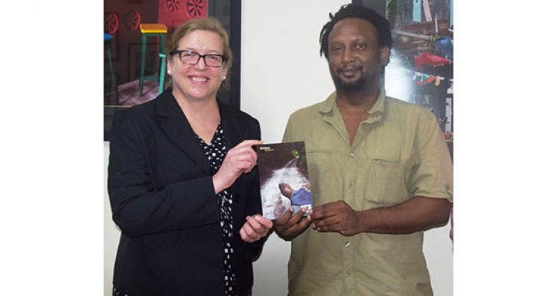 Ruel Johnson presents one of his books to Amanda Cauldwell, Public Affairs Officer of the U.S. Embassy