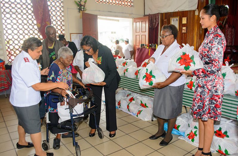 Minister of Public Telecommunications, Cathy Hughes distributes a hamper to 86-year-old Lucille Collymore at the Salvation Army Christmas Hamper Distribution yesterday (Samuel Maughn photo)