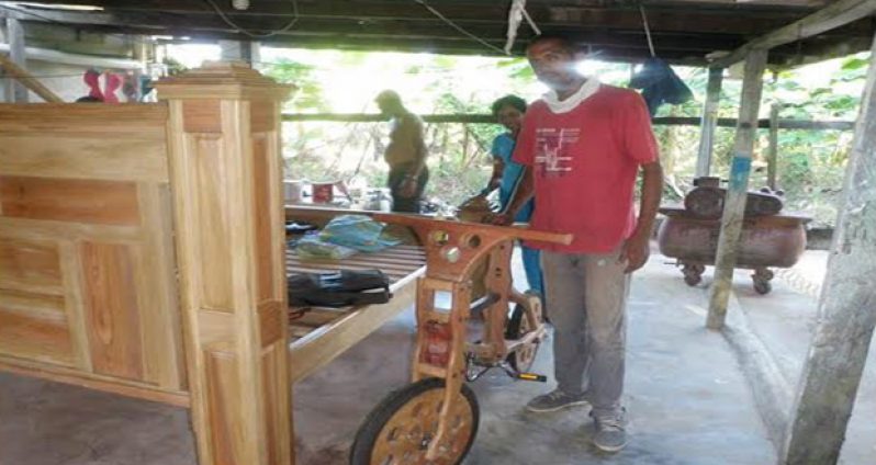 A proud Sazim Bacchus with his wooden bike