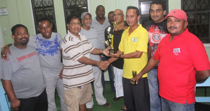 SPONSOR Scotty Patel Ramroop (right) of SPR Enterprise hands over the winning trophy to International Six skipper Manniram “Packer” Shew in the presence of other members of the victorious team