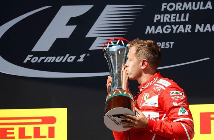 Ferrari's Sebastian Vettel celebrates winning the race on the podium and kissing the trophy
