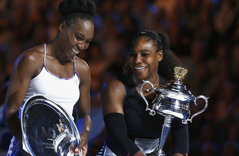 Serena Williams, right, holds the trophy after winning the 2017 Australian Open women's singles title.