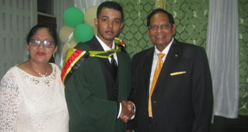 Valedictorian Sasenarine Tomby shakes hands with Prime Minister Moses Nagamootoo in the presence of Seeta Nagamootoo,  the Prime Minister’s wife