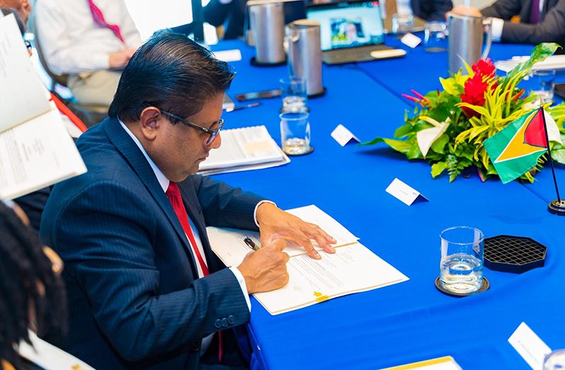 Senior Minister with Responsibility for Finance, Dr. Ashni Singh signing one of the loan agreements