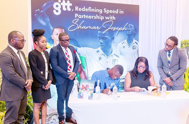 Shemar Joseph (fourth from right) signs his three-year contract as a GTT brand ambassador with Chief Commercial Officer, Kerchelle Jn Charles (fifth from right), in the presence of Joseph’s team and GTT staff (Delano Williams photo)