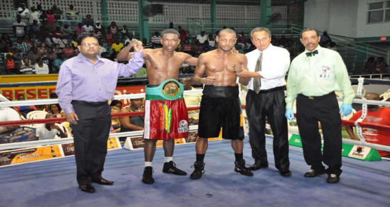 Finance Minister Dr. Ashni Singh (extreme left) raises Guyana’s Clive Atwell’s hand into the air after the Guyanese won the WBC CABOFE Junior Welterweight title on Saturday night. Second from right is GBBC’s president Peter Abdool. Referee Eion Jardine is at extreme right (Denalo Williams photo).