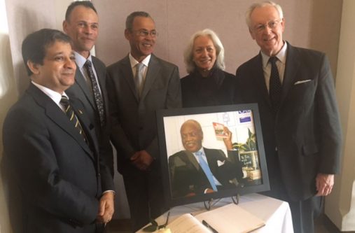 sir Ambassador Dr. Riyad Insanally, (at left) Braithwaite's two sons, Francis and Ron, his wife Ginette, and a friend stand around a portrait of the author and the book of condolence. (Francis Quamina Farrier photo)