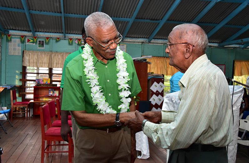 President David Granger interacts with an elderly resident of East Bank Berbice at the conclusion of the community meeting