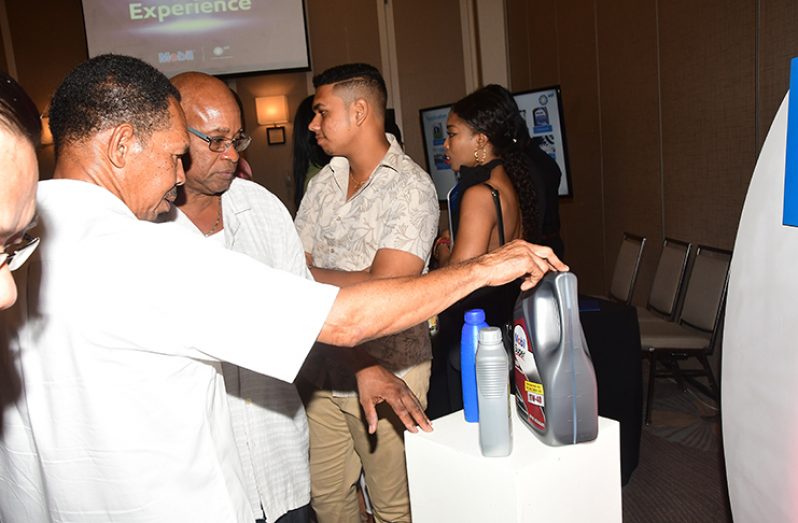 Some of the attendees at Friday’s launch check out some of the Exxon lubricants that will be available through Sol (Adrian Narine photos)