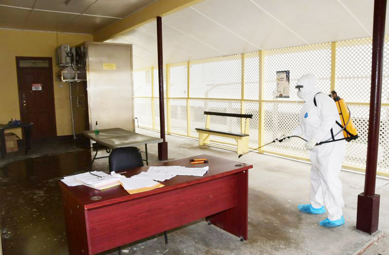 A health worker sanitises a public building in April 2020. (Adrian Narine/Guyana Chronicle)