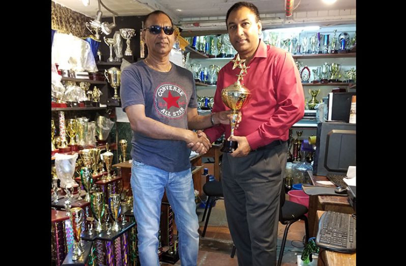 Lusignan Golf Club president Aleem Hussain (right) accepts the winners’ and other trophies from Ramesh Sunich, proprietor of Trophy Stall.