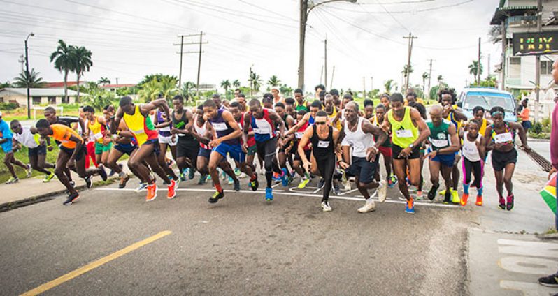 Athletes from across Guyana move off for the start of the Professional Key Shop/Windjammer Hotel sponsored `Golden Mile’ Road Race yesterday from outside the Club 704 Sports Lounge. Fourth from left is  race-winner Winston Missigher.
