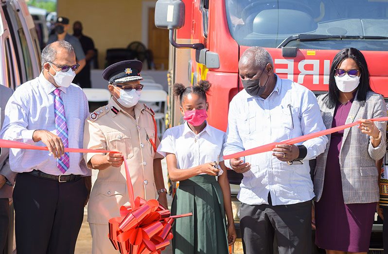 A student, with the assistance of Home Affairs Minister, Robeson Benn, cuts the ribbon to officially commission the Melanie Damishana Fire Station. Also pictured are Minister of Health, Dr. Frank Anthony; Fire Chief Kalamadeen Edoo; and Permanent Secretary in the Home Affairs Ministry, Mae Toussaint