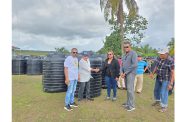 A resident receives a black tank from PPP/C Member of Parliament Dr Tandika Simone Smith as officials and other residents look on