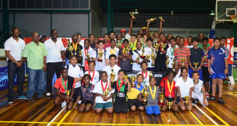 An elated group of young table tennis winners pose with their spoils after the completion of the Digicel Inter-School table tennis championships at the Cliff Anderson Sports Hall last night. Looking on approvingly from left are national coach Linden Johnson, GTTA president Godfrey Munroe and Digicel’s Gavin Hope. (Adrian Narine photo)