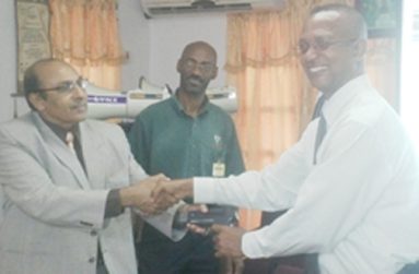 GOA President, K. A. Juman Yassin (left) hold the start gun of the FAT System with AAG President, Aubrey Hutson, while GOA Official Garfield Wiltshire (centre) looks on.