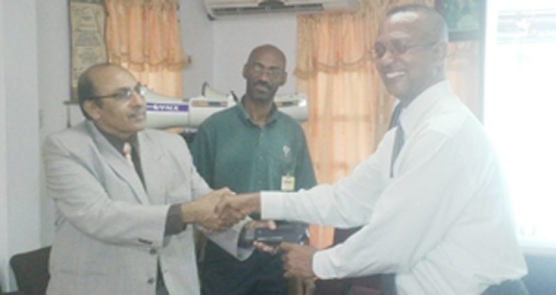 GOA President, K. A. Juman Yassin (left) hold the start gun of the FAT System with AAG President, Aubrey Hutson, while GOA Official Garfield Wiltshire (centre) looks on.