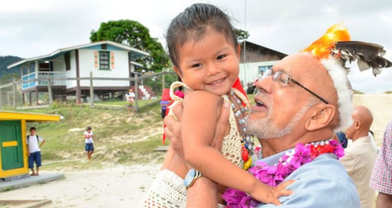 President Donald Ramotar sweeps up a toddler as he arrives at Paramakatoi to lead the cash grant distribution