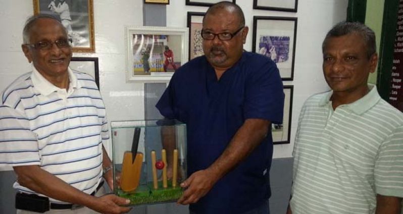 Deopaul Raghubir (left) the grandfather of Omesh Mohammed, presents the turf from the ‘square’ at Lord’s, along with a wicket, ball and bat ornament to GCC president Lionel Jaikarran, while Prem Raghubir looks on appreciatively at right.
