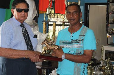 Proprietor of the Trophy Stall, Ramesh Sunich (right) handing over the champion’s jockey trophy for the Kennard’s Memorial Turf Club (KMTC) Boxing Day meet to president of the KMTC, Cecil Kennard.