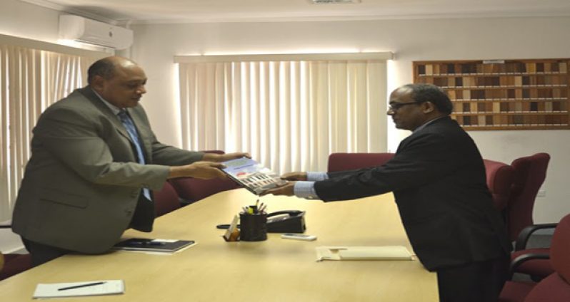 Minister Trotman presents a copy of his book to Indian High Commissioner Venkatachalam Mahalingam