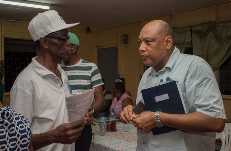 Minister of Natural Resources, Hon. Raphael Trotman listening to Campbellville resident, Ivor Anderson, following a community meeting