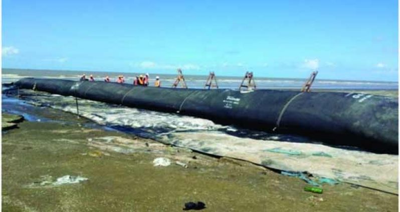 Ministry of Public Works technicians installing the first geotextile tube groyne to be constructed at the Kingston - Kitty foreshore (photo courtesy Ministry of Public Works)