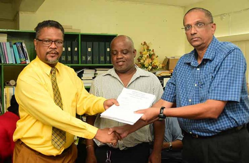 CLO Charles Ogle hands the agreement to CEO of Sterling Products Limited, Ramsay Ali in the presence of CCWU President, Sherwood Clarke (Adrian Narine photo)