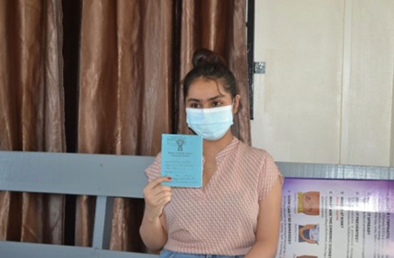 Crystallanne Ramrattan holds up her COVID-19 Vaccination Card. Guyanese will now be required to be vaccinated to access public buildings (DPI photo)