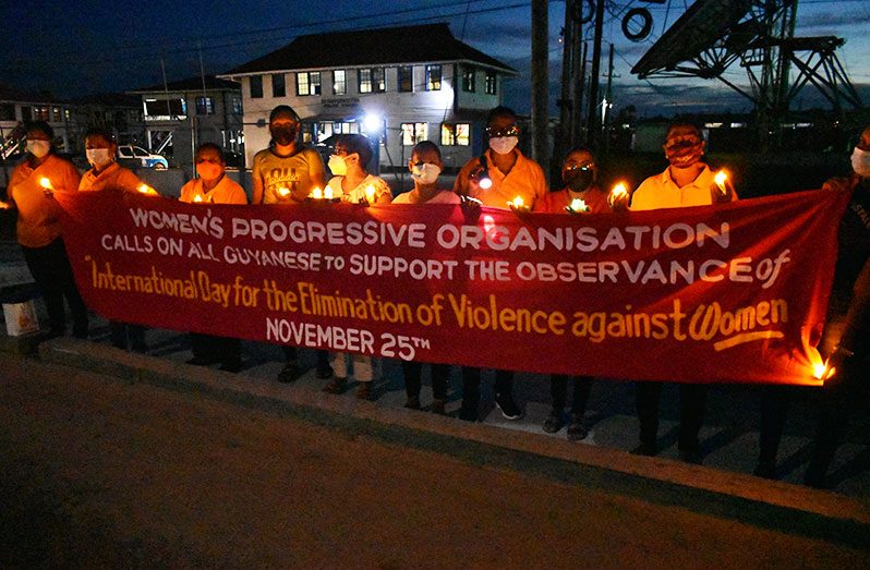 Members of the Women’s Progressive Organisation showcasing their banner on Thursday at the candlelight vigil at Beterverwagting, East Coast of Demerara